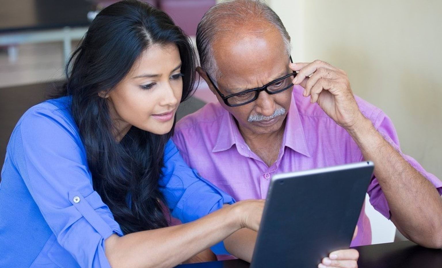 Two people looking at a laptop together. One is pointing at the screen while the other is watching closely.