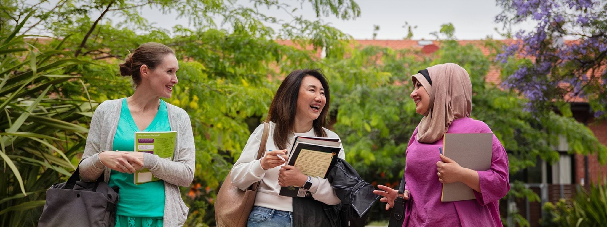 Three students walking next to each other outside, smiling.