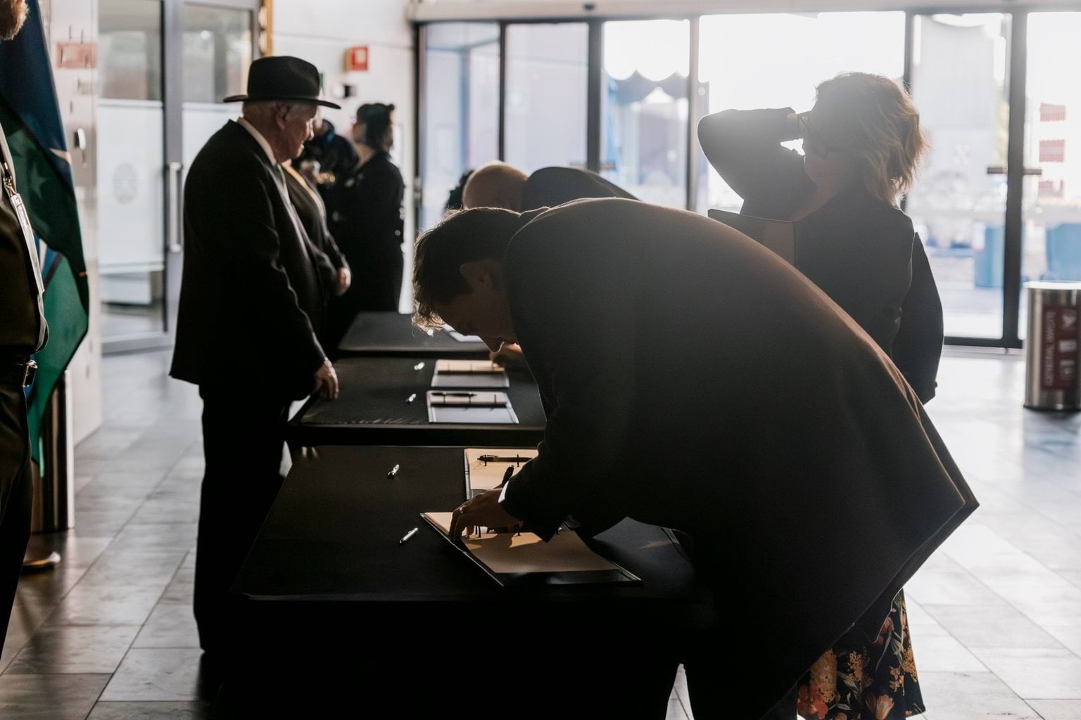 A person in a dark jacket signs a book.