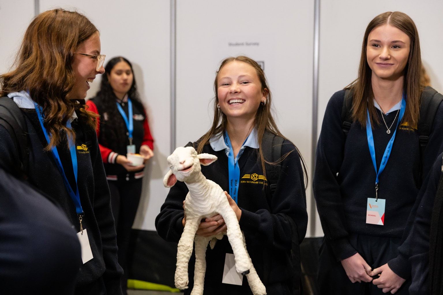 Female students holding an artificial lamb from the birthing demonstration