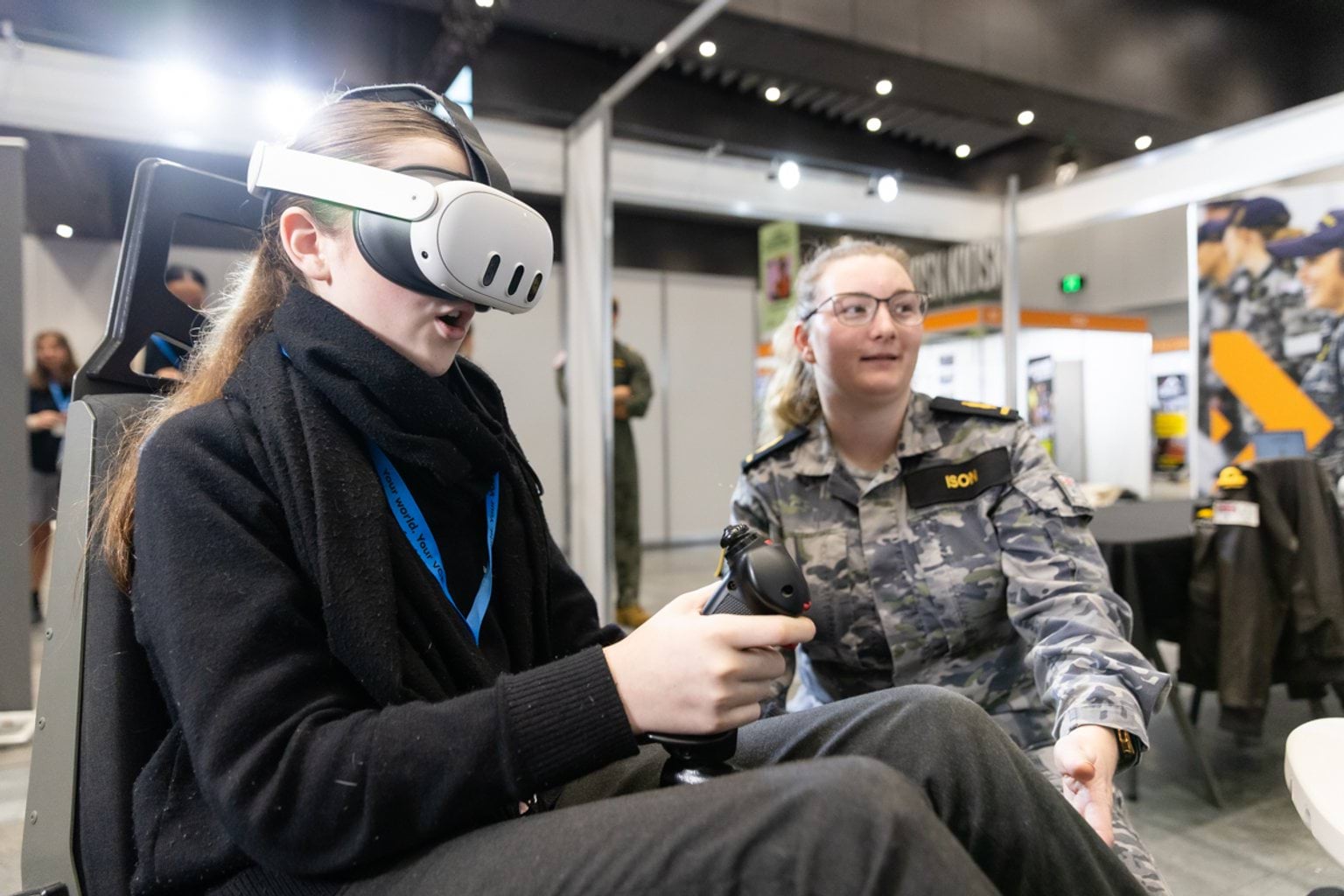 Female student using a virtual reality simulator with the supervision of a female member of the defence force