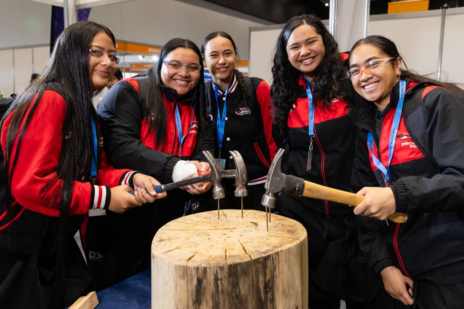 Female students practicing woodwork hammering nails into wood