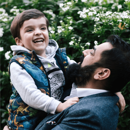 Man holding boy and looking up at boy smiling.