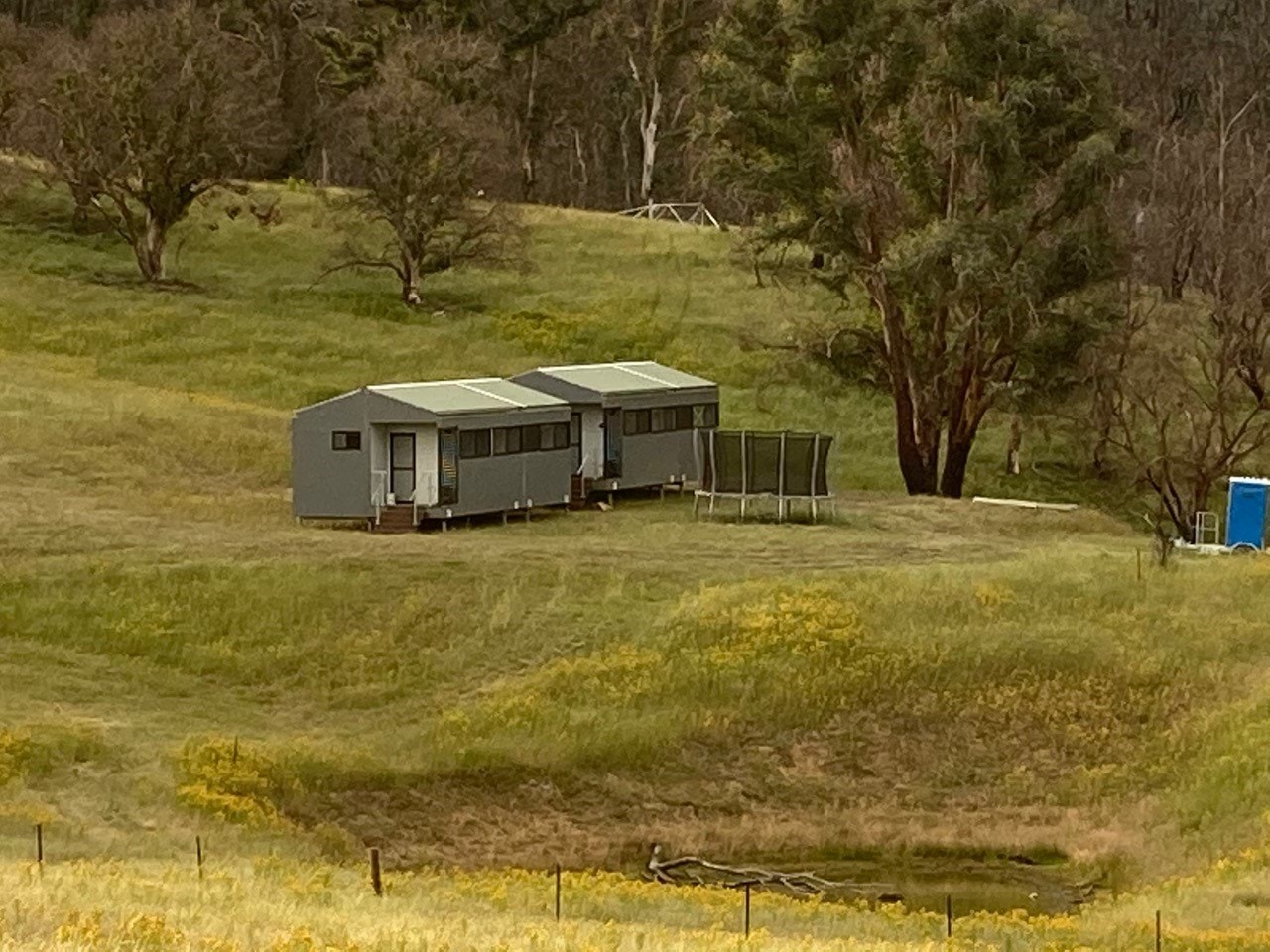 A modular house in the middle of a grassy paddock.