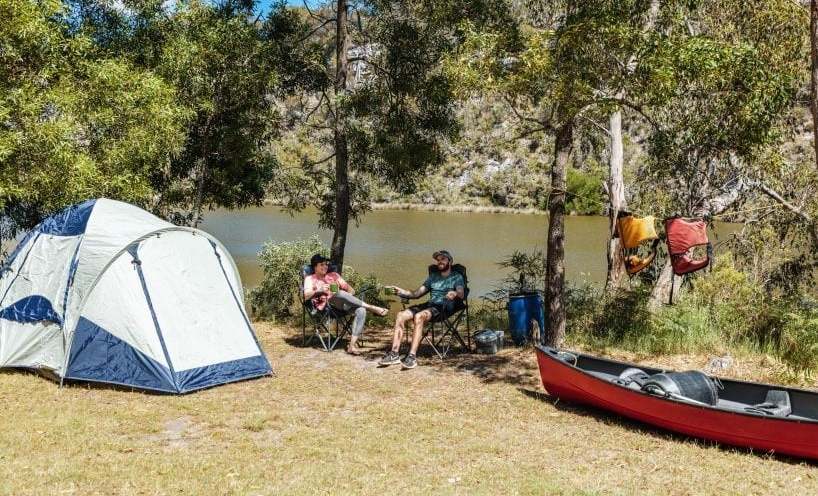 Two people sitting outside a tent at Forest South campground