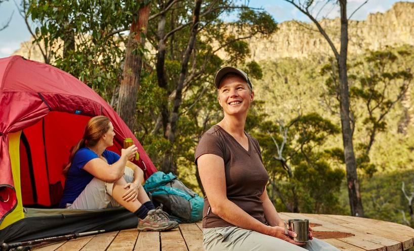 Two people camping sitting outside a tent