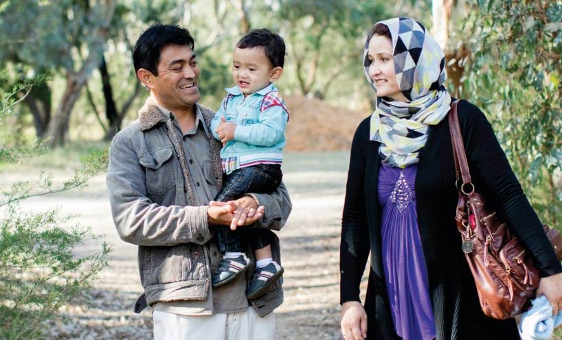 Two adults and a child walking in a park