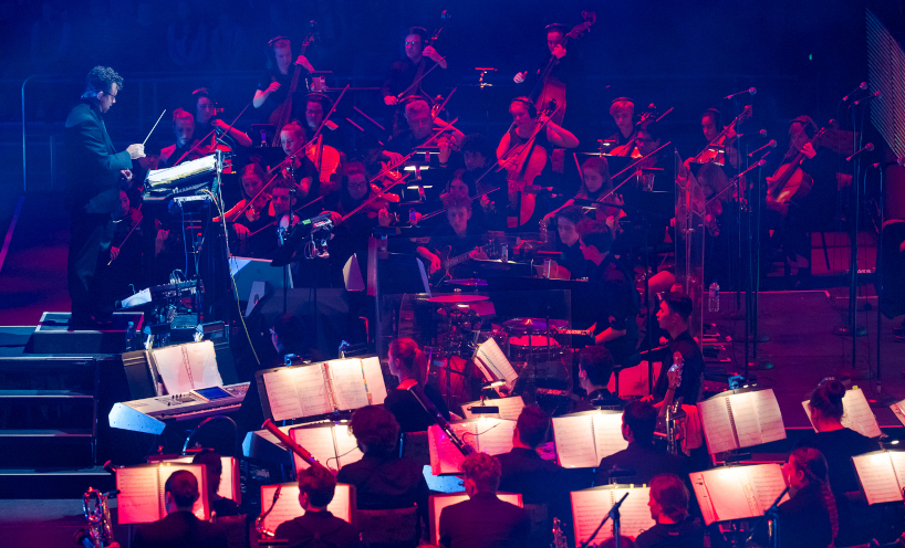 Student orchestra playing in a large auditorium