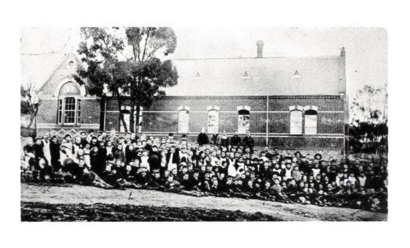 Whole school portrait outside brick Maldon State School building around 1875.