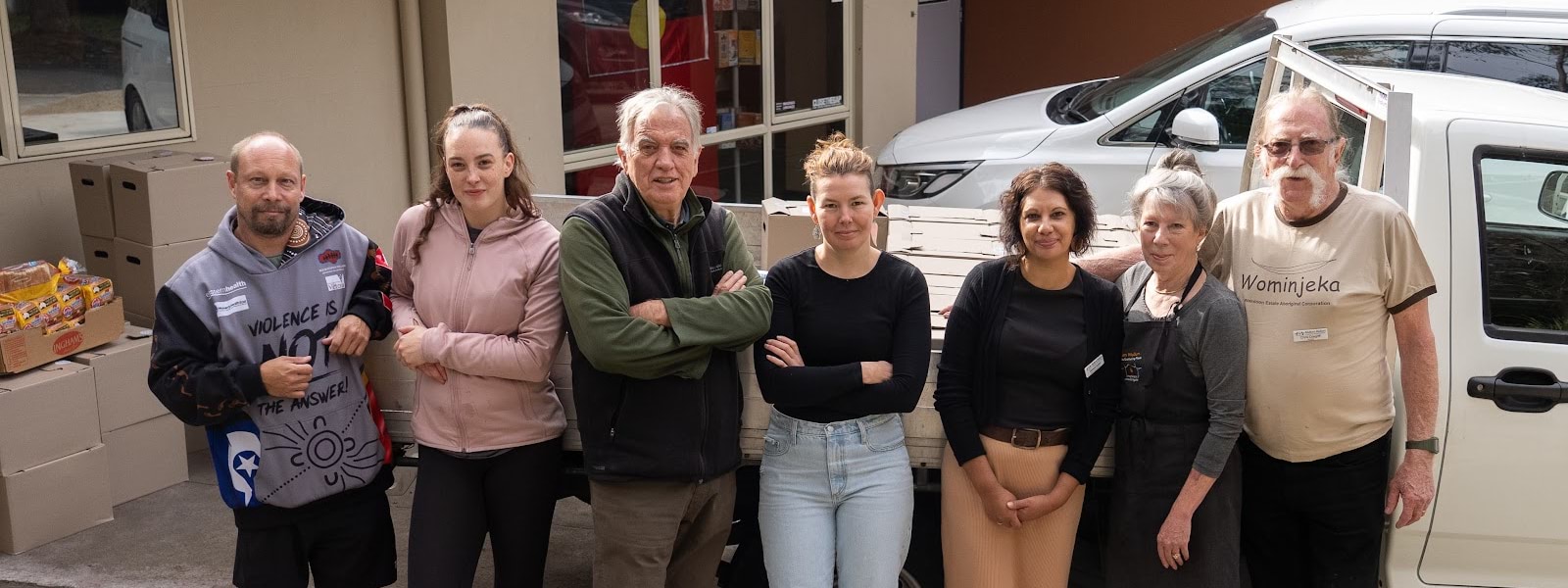 Line of women and men standing in front of a vehicle