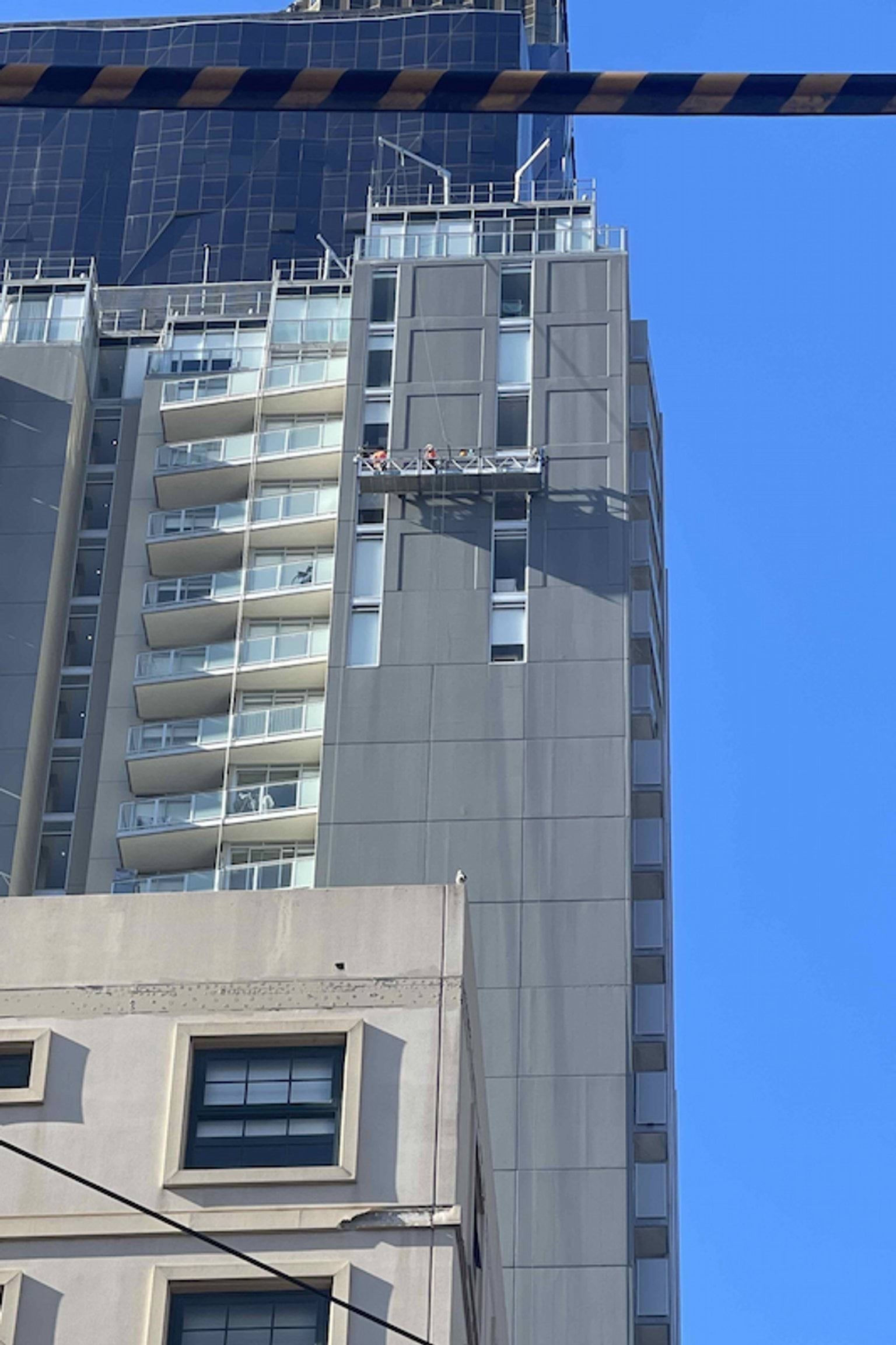 People working on a platform on the side of a high-rise building.