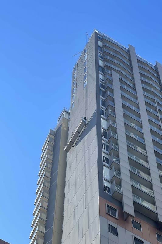 People working on a platform on the side of a high-rise building. 