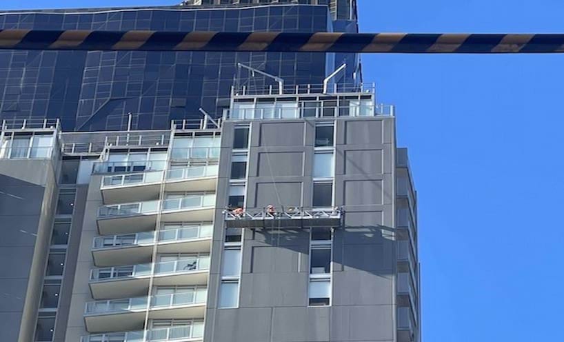 People working on a platform on the side of a high-rise building. 