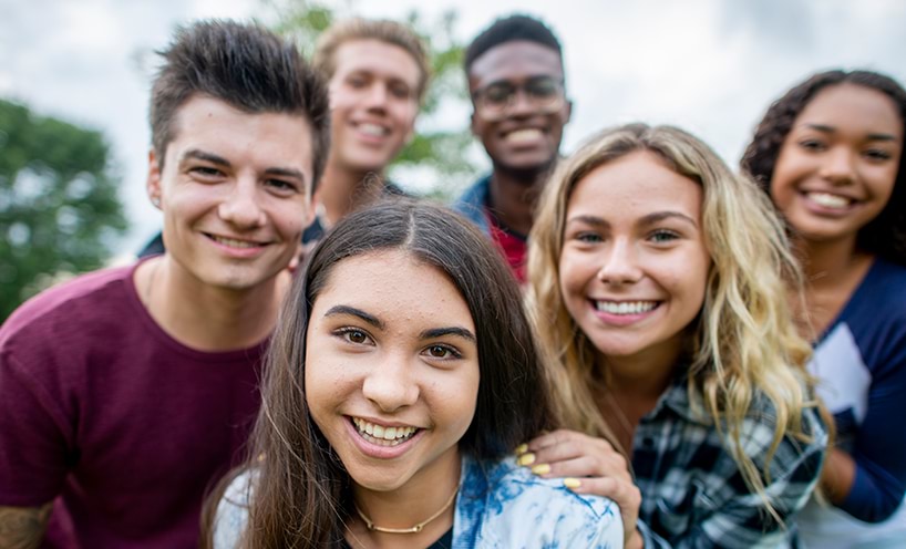 A group of diverse teenage friends smiling and looking into the camera, selfie-style