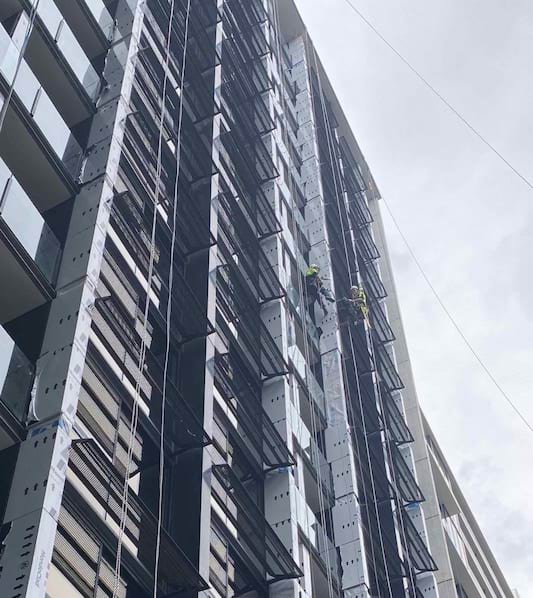 Workers using abseils to rectify cladding panels