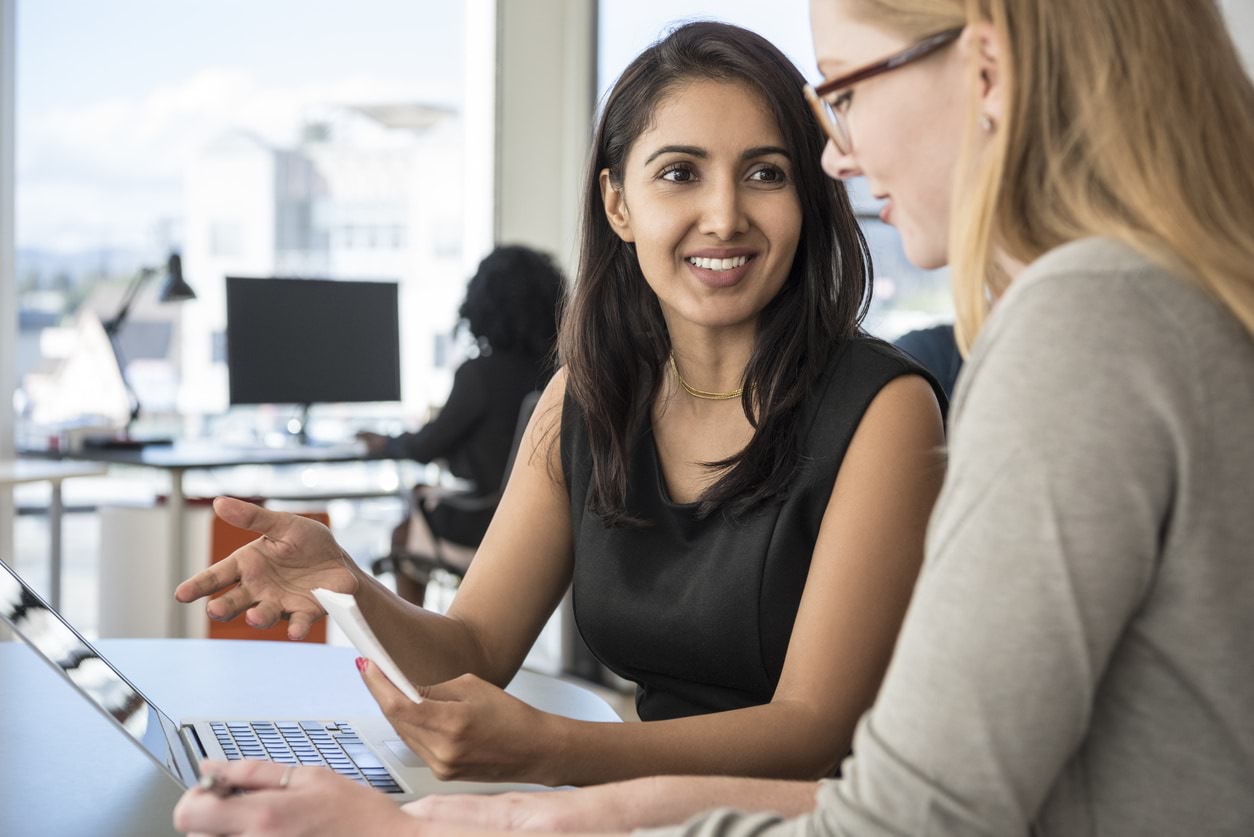 Two women working at a laptop.