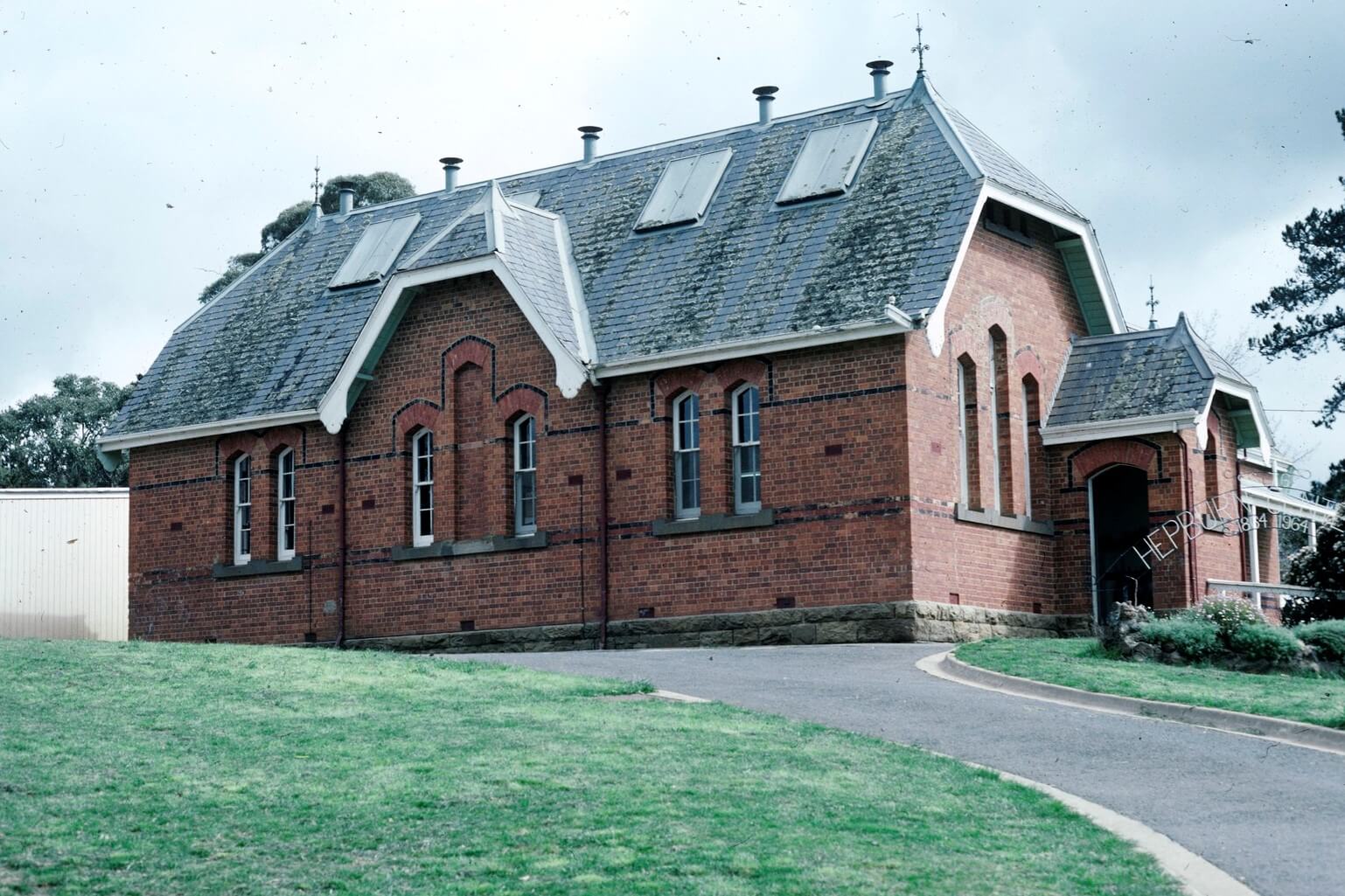 Photograph of the Hepburn Primary School building. The building is brick and the school's centenary glates are near the door to the building. 