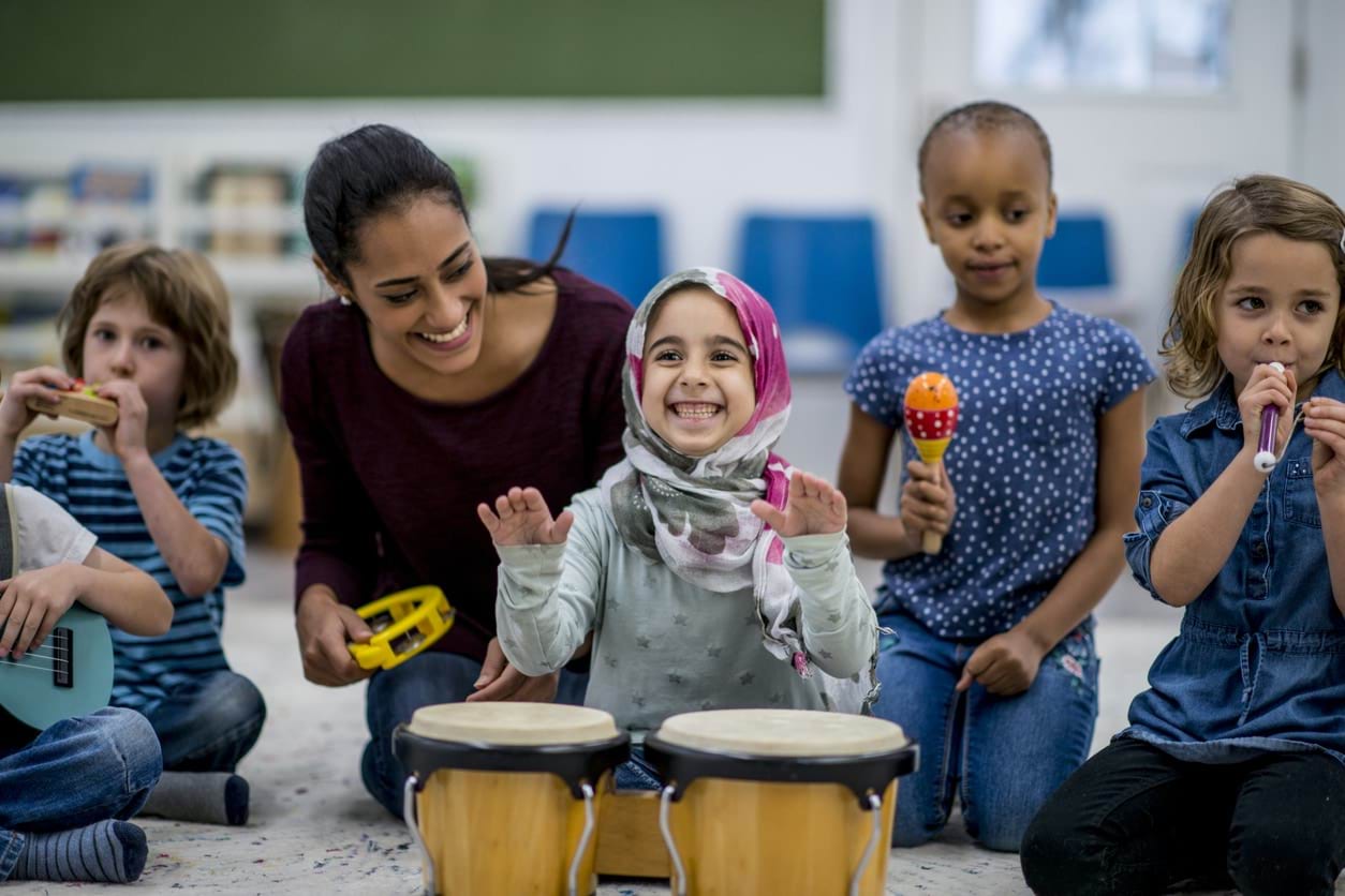 Children playing with musical instruments with a teacher.