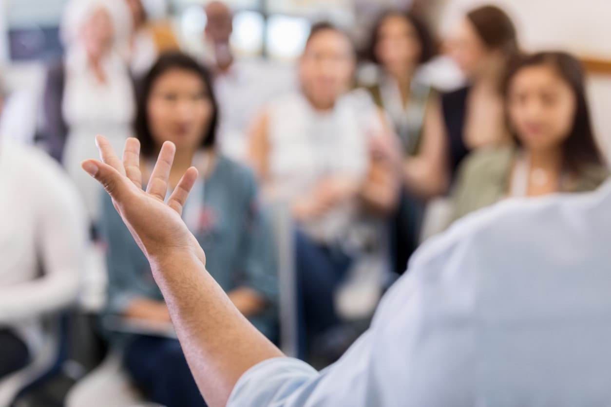 People in an audience listening to a public speaker.