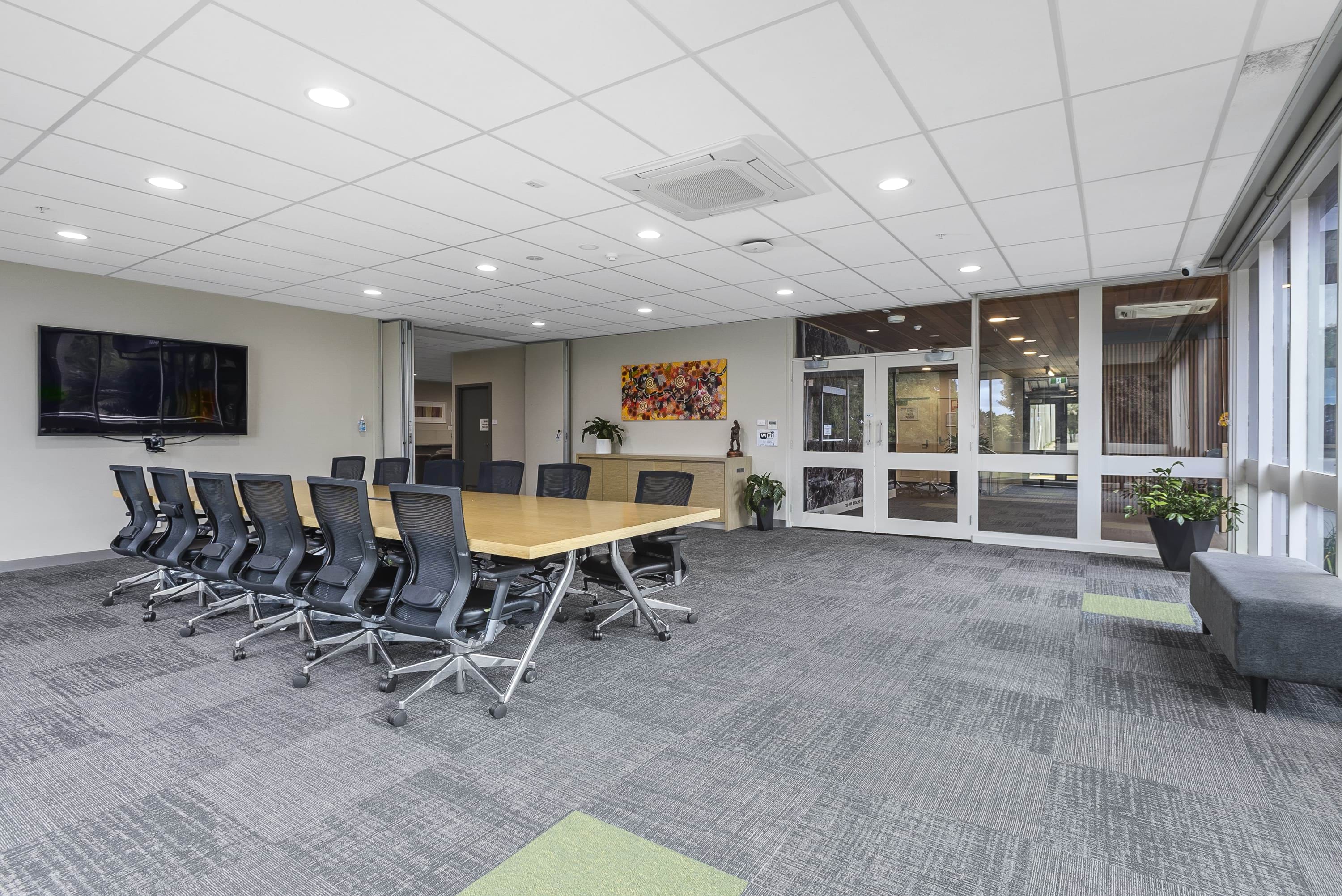 image shows the boardroom at the VEMI conference centre. There is one large table with 12 chairs around it.