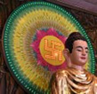 Statue of Buddha with a multicoloured circle that has the sacred Swastika behind his head