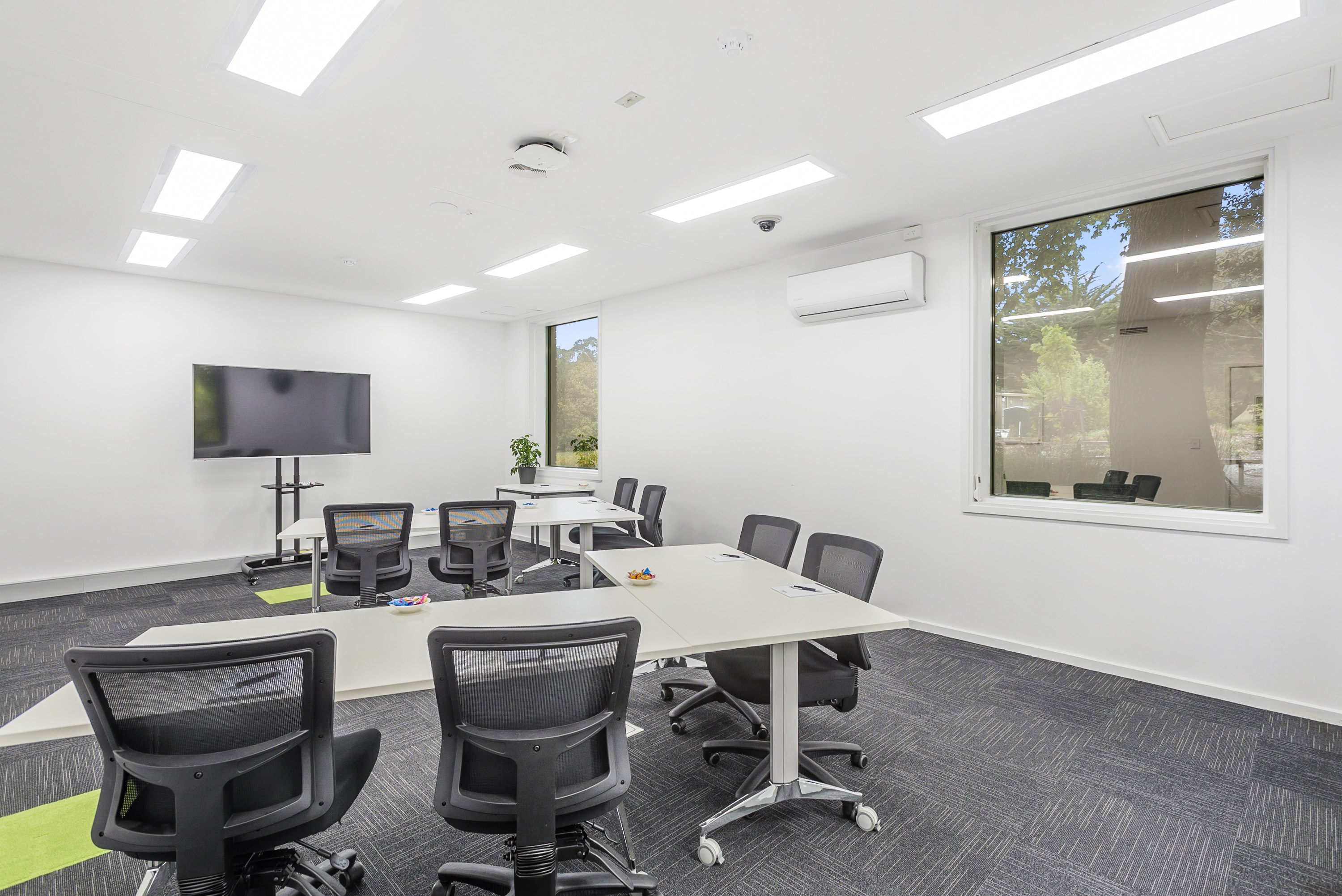 Image shows one of the Syndicate meeting rooms at the VEMI Conference Centre with a screen, tables and chairs.