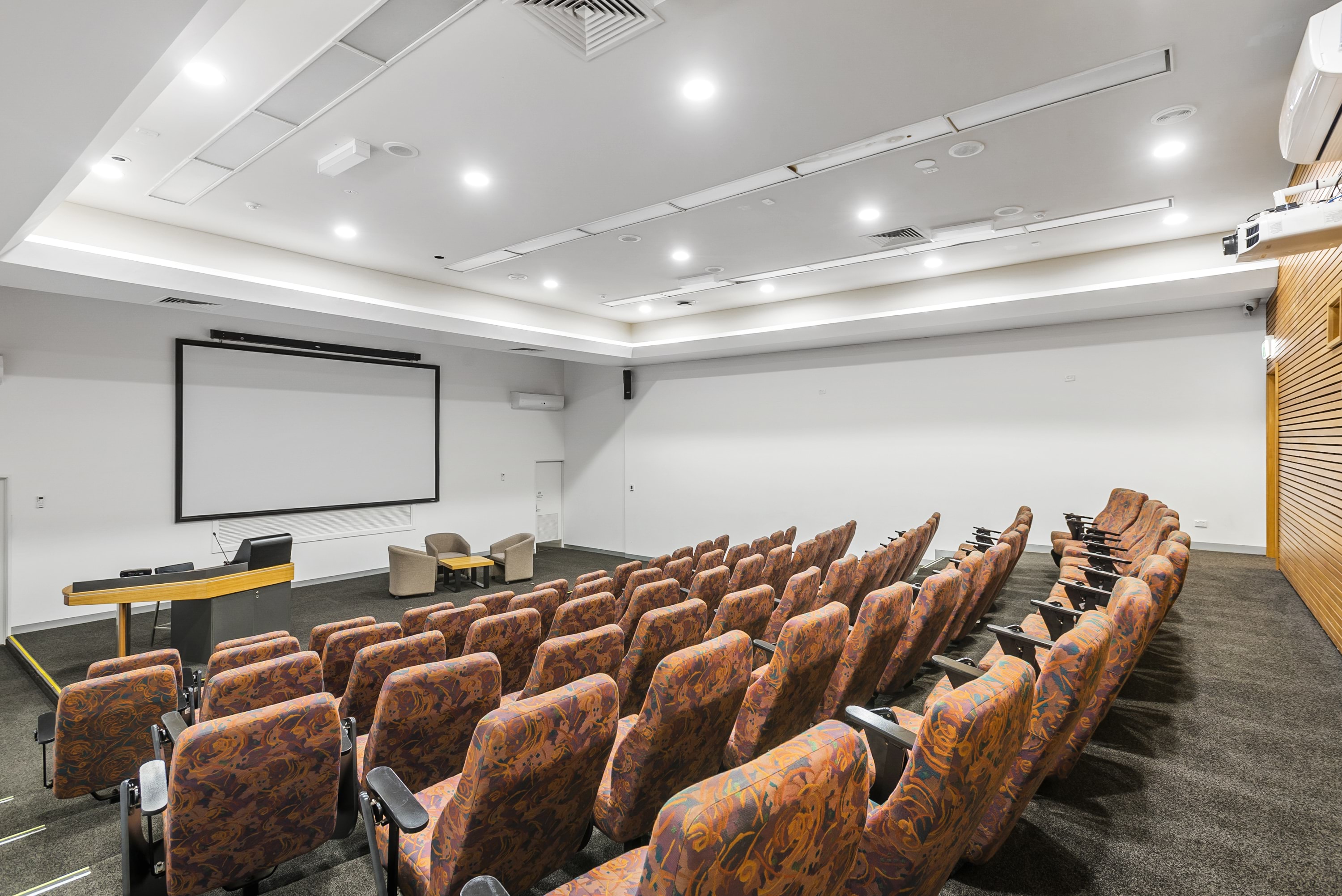 Image shows the theatre at the VEMI Conference Centre. There is a large screen and cinema style seating.