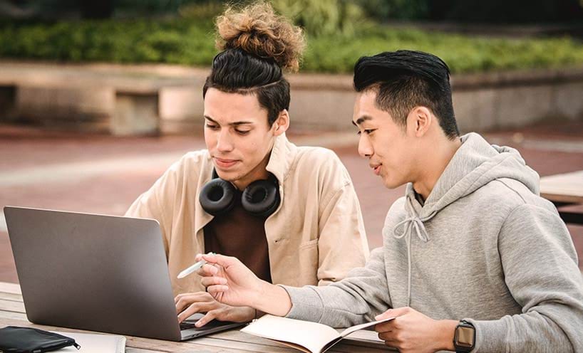 Two students talking and looking at a laptop