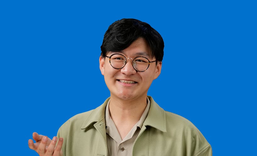 A male graduate in front of a blue background