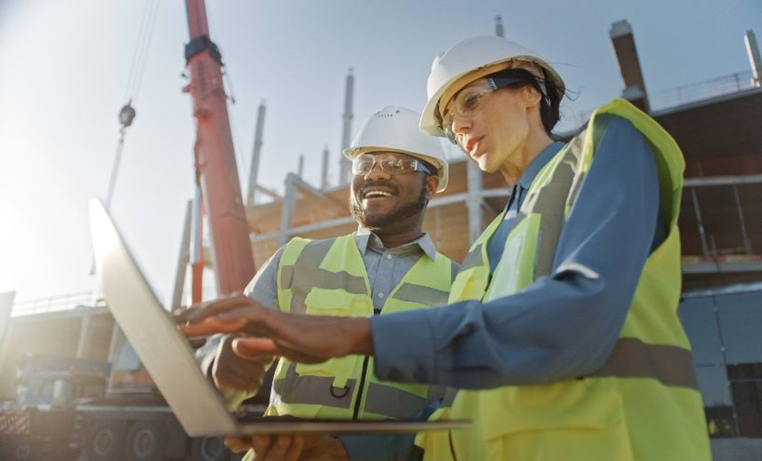 Two people looking at a laptop on construction site Two people looking at a laptop on construction site