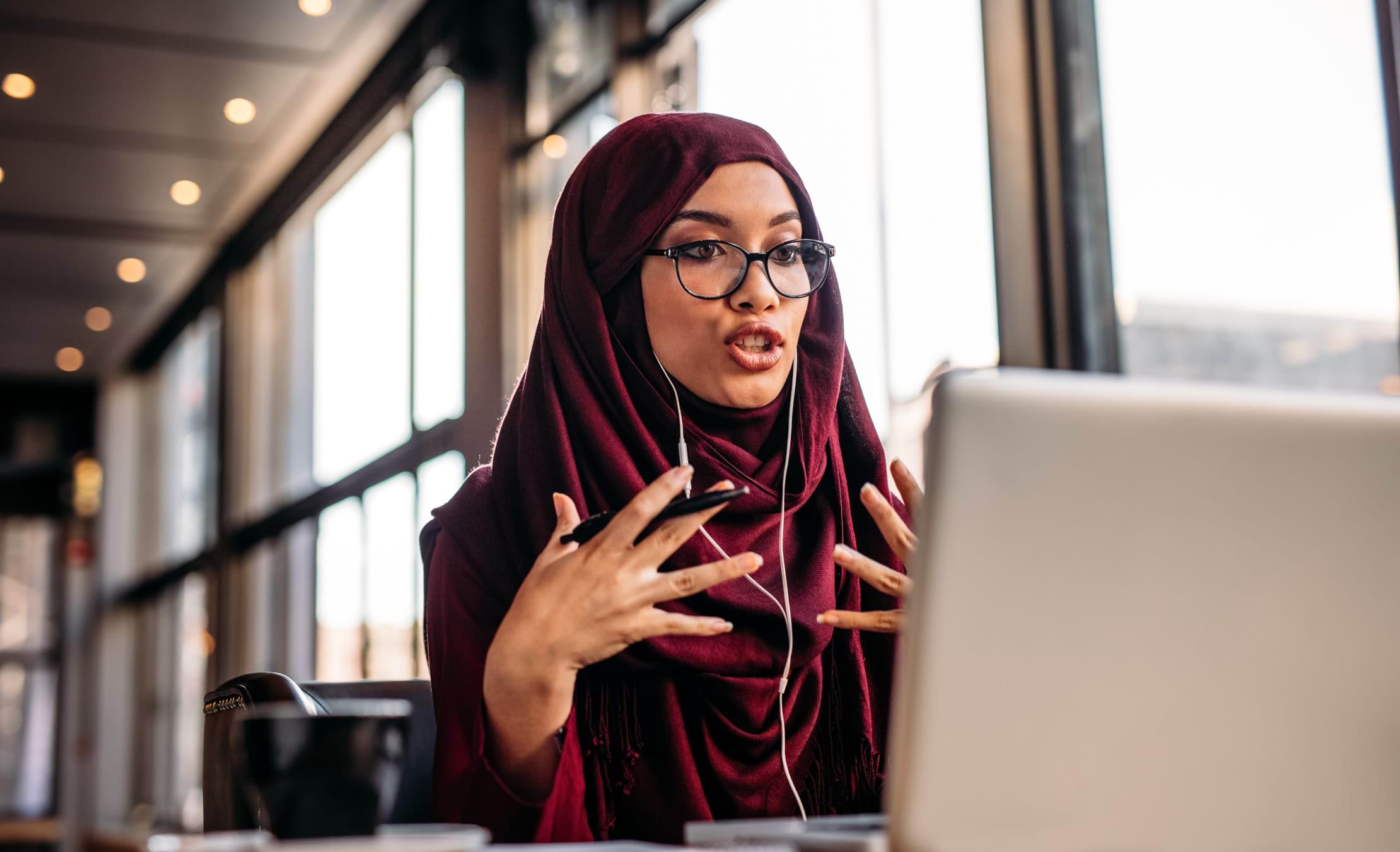 Woman wearing headphones and talking to someone via a computer