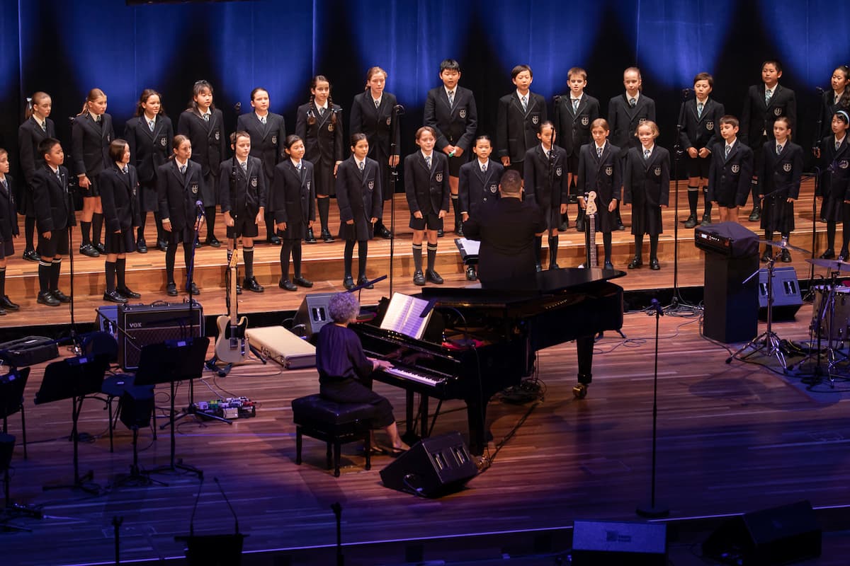 A group of school students sing on stage.