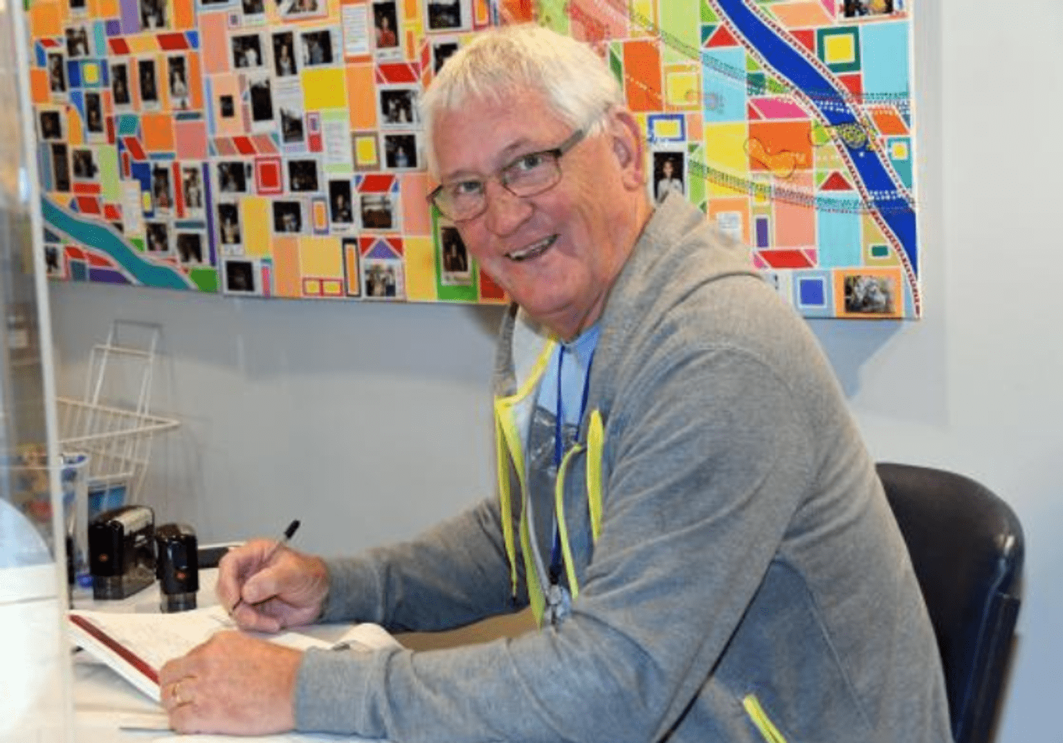 a Justice of the Peace happily posing as he signs documents at a DSS