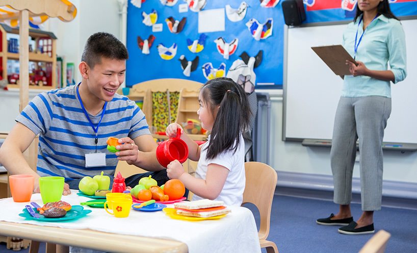 A teacher showing toys to a student in a classroom.