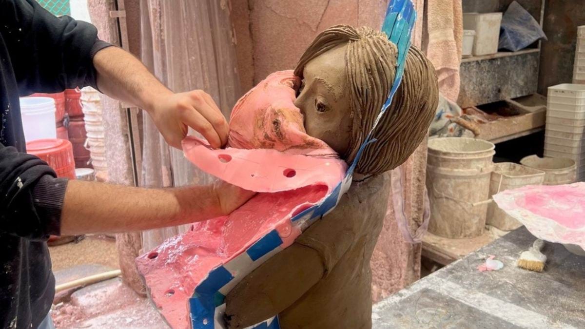 An artisan carefully removes the silicone moulding from the clay sculpture of Stella Young.