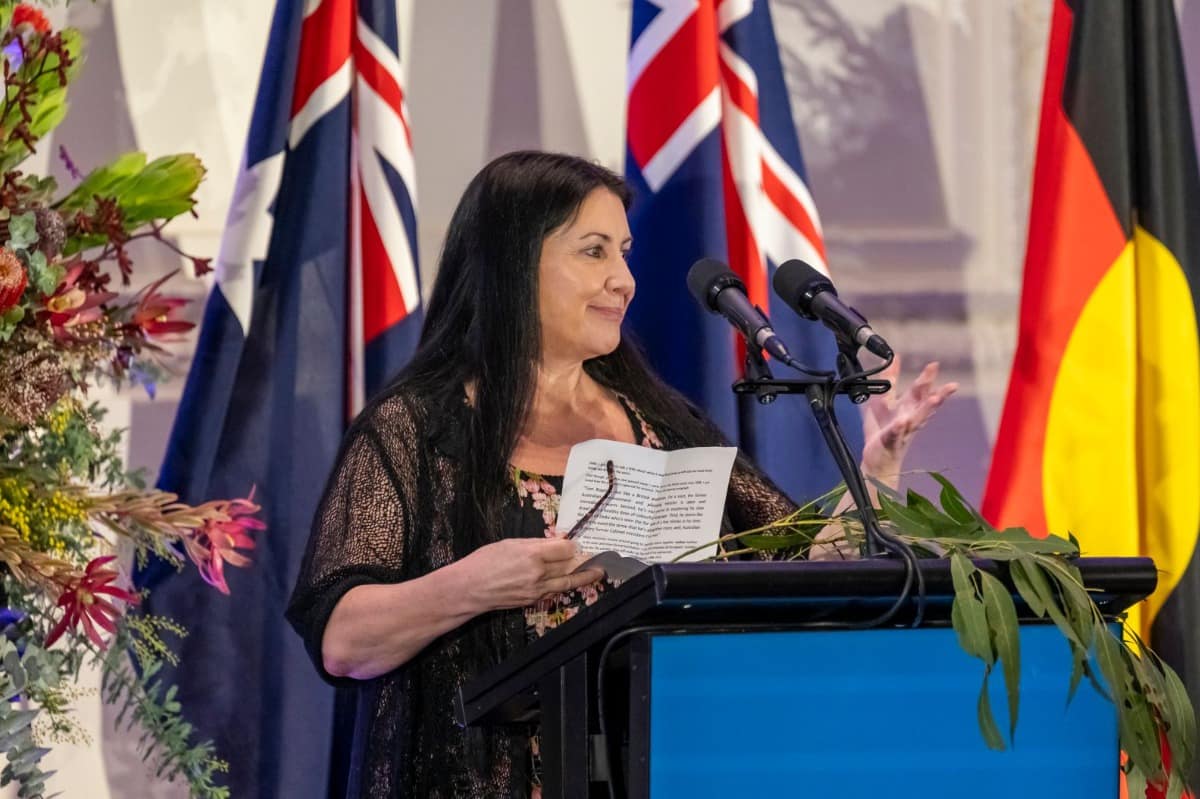 A woman stands at a podium speaking into a microphone. 