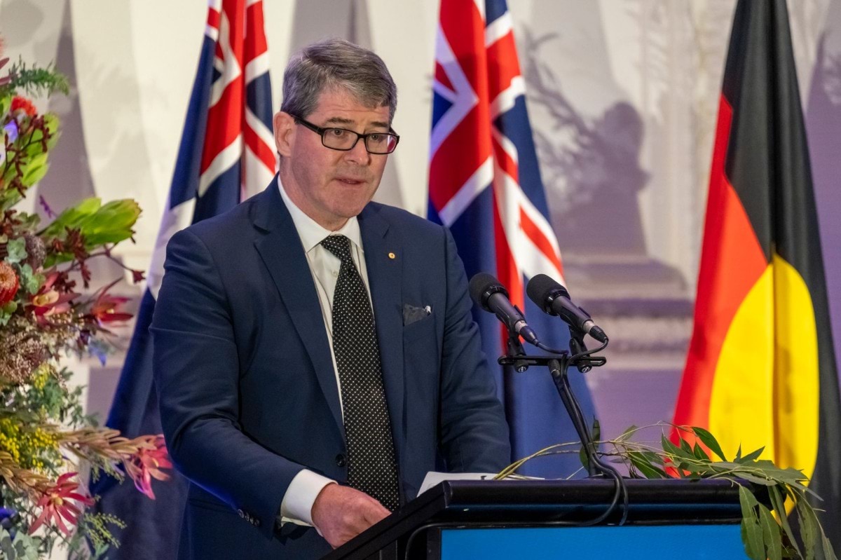 A man stands at a podium speaking into a microphone. 