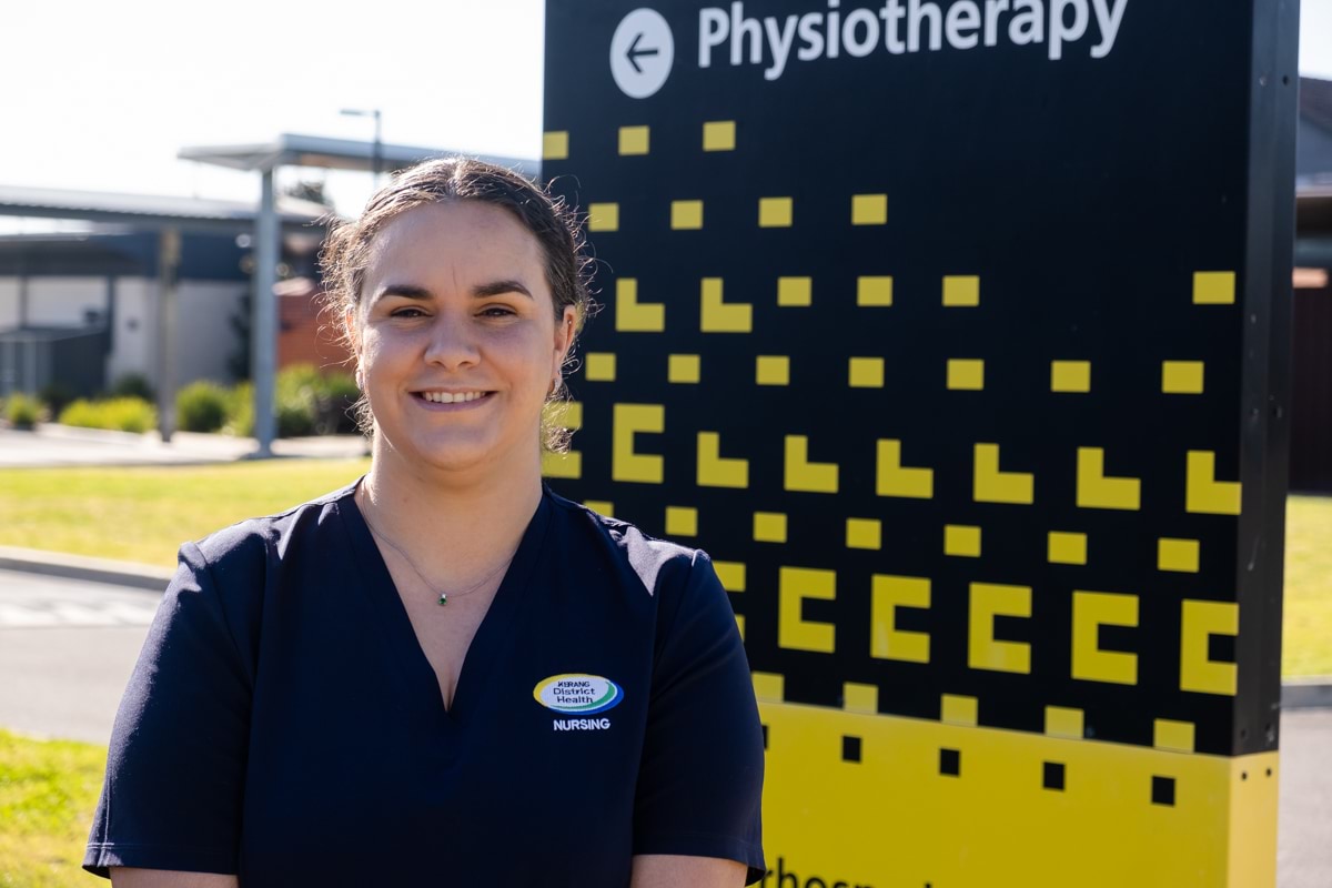 Pearl Dunn Victorian Training Awards 2023 Koorie Student of the Year winner outside health workplace with physiotherapy on a board behind her