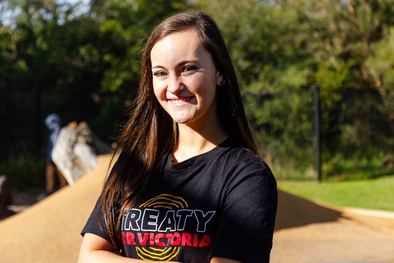 2023 Victorian Training Awards Koorie Students of the Year finalist Jenaya Bartlett smiling at the camera wearing a 'Treaty for Victoria' t-shirt