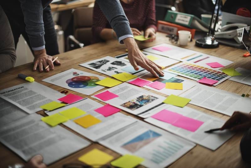 Hand placed on sticky notes laid out on a table