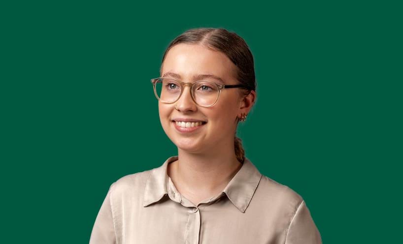 A smiling graduate on a green background