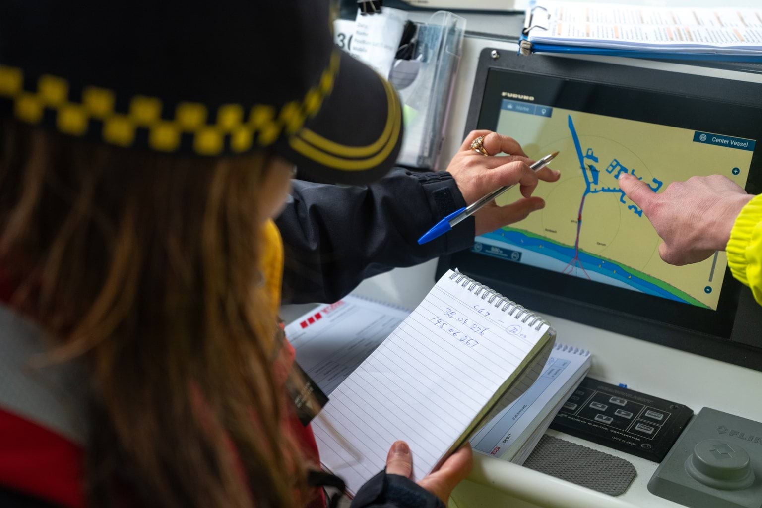 Image shows a MSAR crew member pointing at a navigation unit on a boat