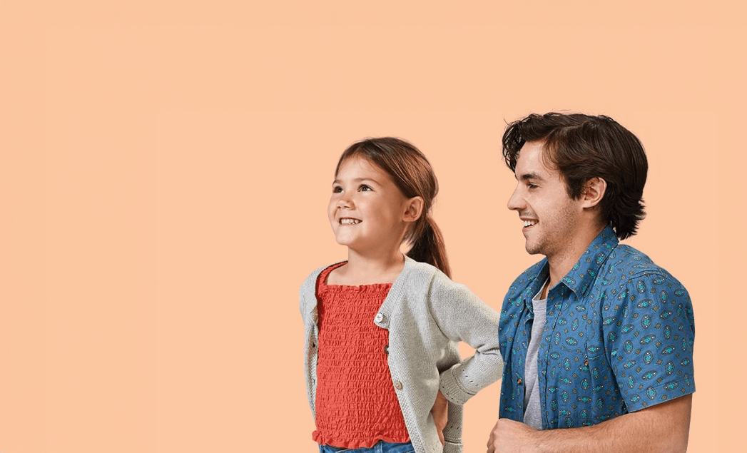 A young girl and a man smile against a light orange background.