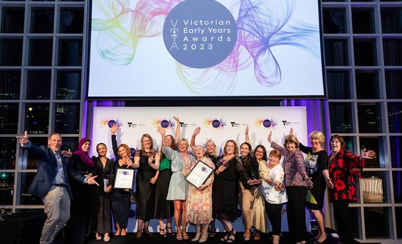 A group of VEYA award winners stand in a line and are celebrating their awards. Their hands are held up and they are smiling towards the camera. 