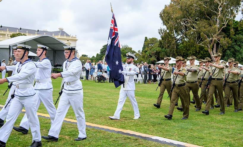 Guard of honour showing soldiers marching with the Australian flag