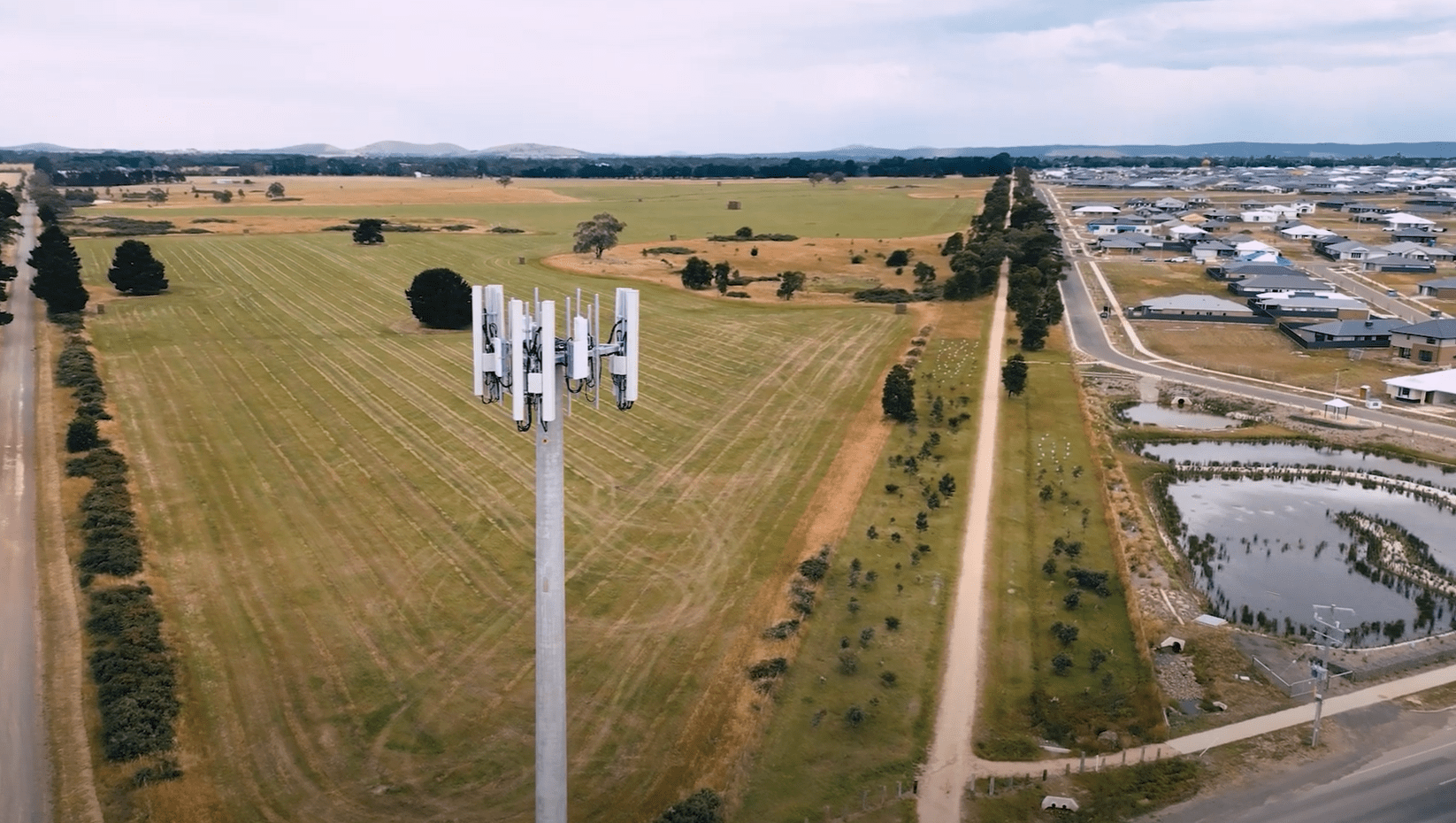 Drone view overlooking a mobile tower in a field with Lucas residential area to the right