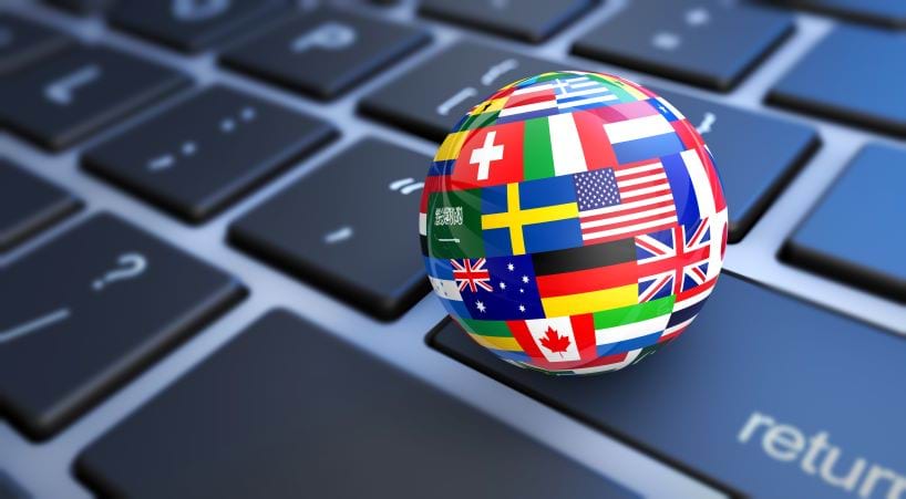 Image of a globe covered in flags of the world sitting on a keyboard.