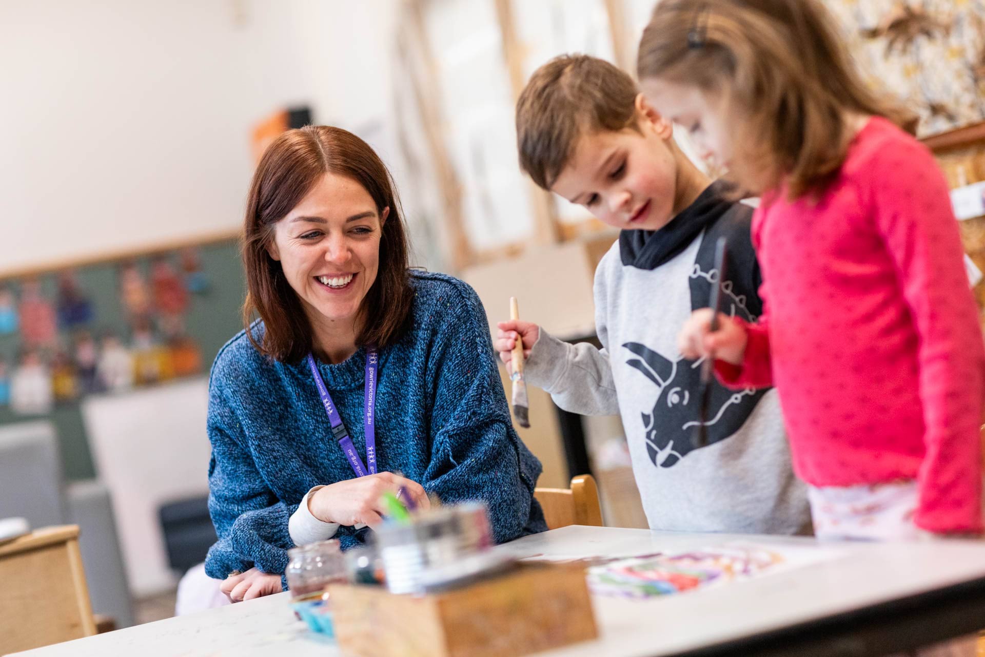 An early childhood educator helps children with a painting activity