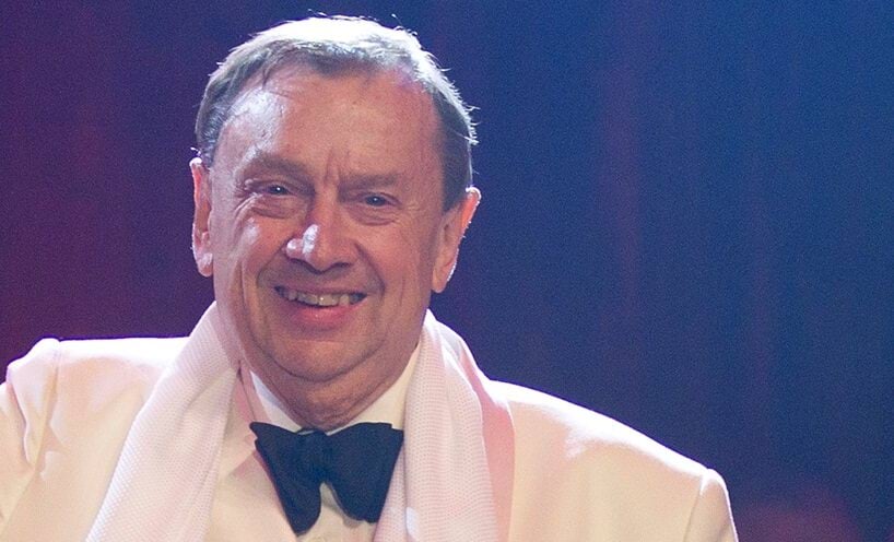 A smiling Harold Mitchell in a white suit and black bowtie