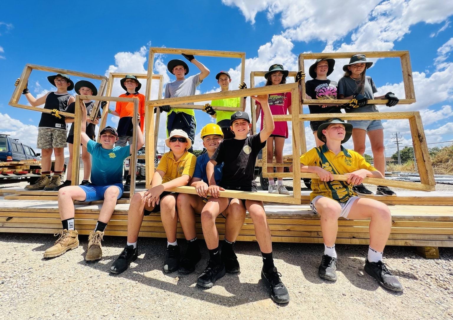 Echuca Primary School Hands on Learning program children Echuca Primary School Hands on Learning program children sitting outside on top of building supplies and holding up wooden frames for their outside project